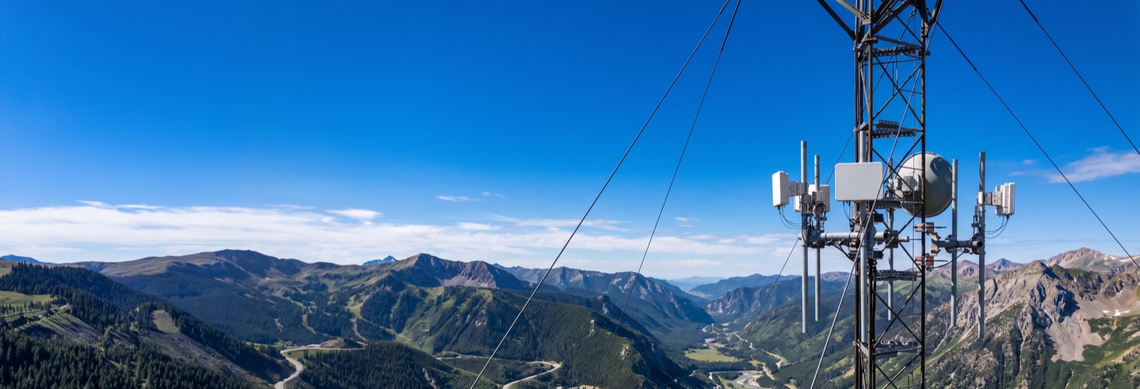Fixed wireless antennas on a guyed tower above a mountain river valley.